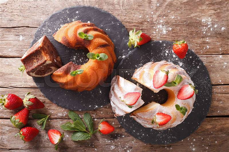 Marble cake and vanilla cake with strawberries close-up on the table. horizontal view from above , stock photo