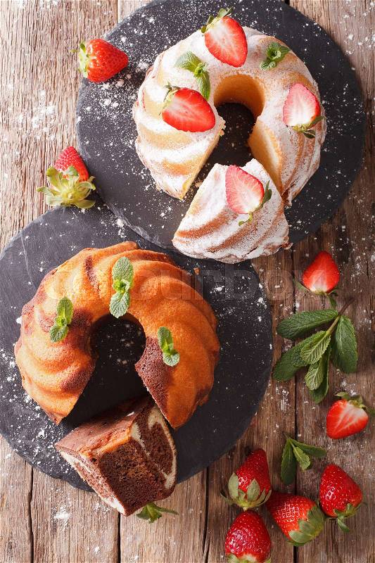Marble cake and vanilla cake with strawberries close-up on the table. Vertical view from above , stock photo