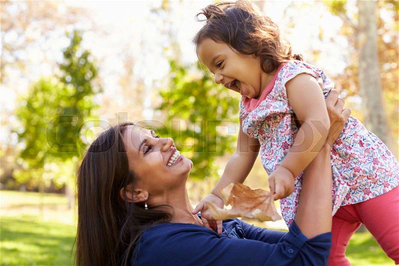 Asian mixed race mum and young daughter playing in park, stock photo