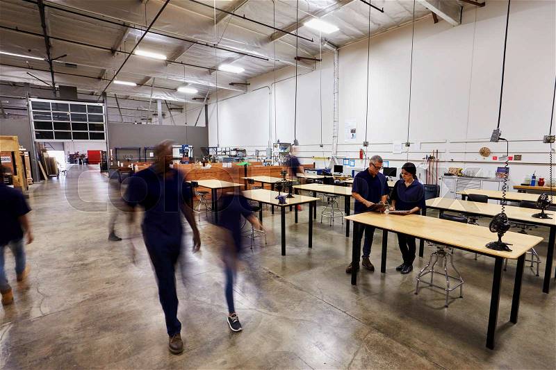 Interior Of Busy Factory With Staff At Work Benches, stock photo