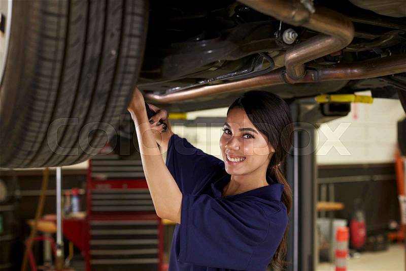 Portrait Of Female Auto Mechanic Working Underneath Car, stock photo