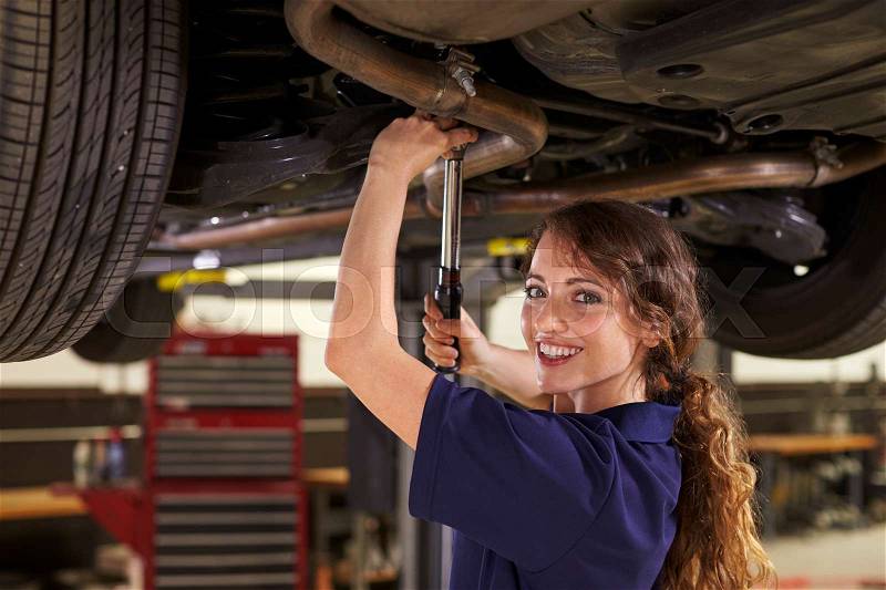 Portrait Of Female Auto Mechanic Working Underneath Car, stock photo