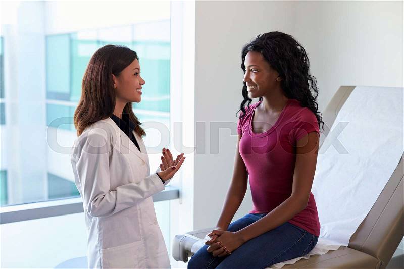 Female Doctor Meeting With Patient In Exam Room, stock photo