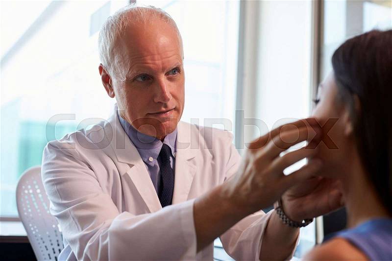 Doctor In White Coat Examining Female Patient In Office, stock photo