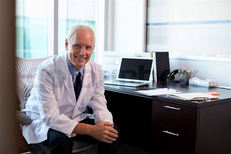 Portrait Of Doctor Wearing White Coat In Office, stock photo