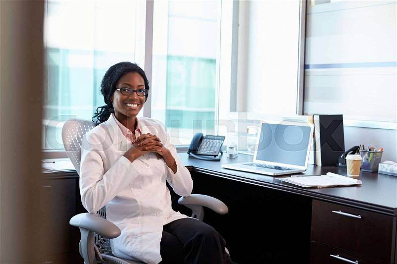 Portrait Of Female Doctor Wearing White Coat In Office, stock photo