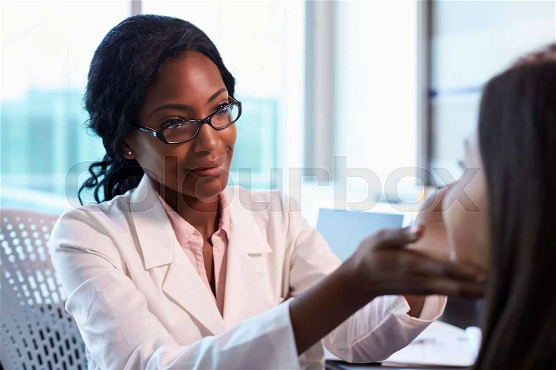 Doctor In White Coat Examining Female Patient In Office, stock photo