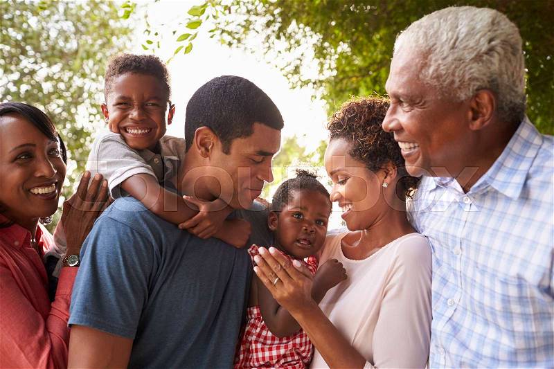 Multi generation black family look at each other in garden, stock photo