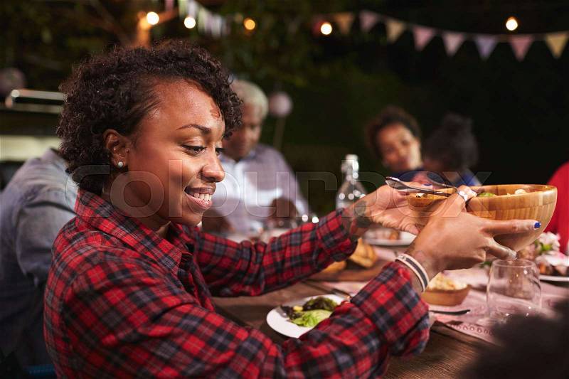 Young black woman passing bowl at a family barbecue, stock photo