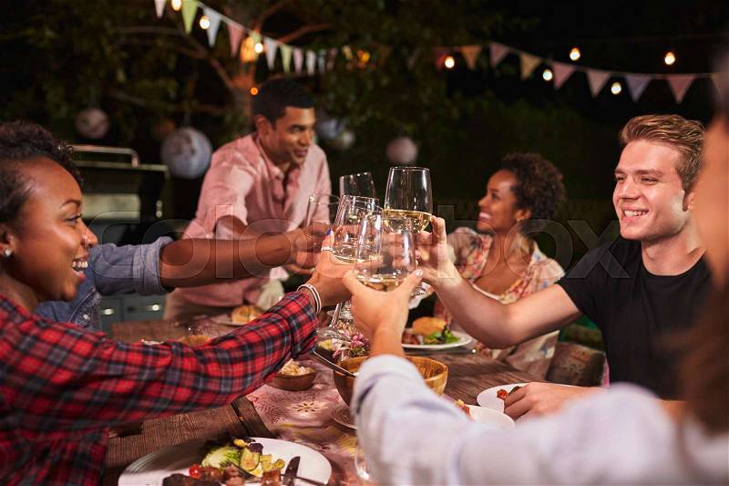 Friends and family toasting at garden dinner party, close up, stock photo