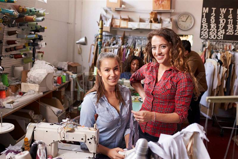 Trainee and manager at clothes design studio look to camera, stock photo