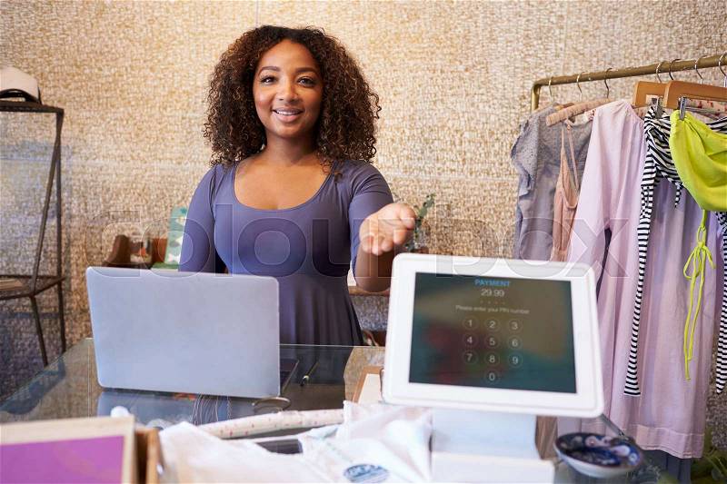 Assistant at clothing store shows computer used for payment, stock photo