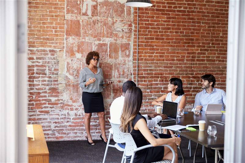 Mature Businesswoman Standing To Address Boardroom Meeting, stock photo