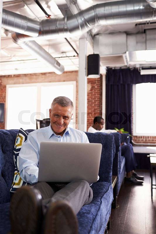 Businessmen Working On Sofas In Relaxation Area Of Office, stock photo