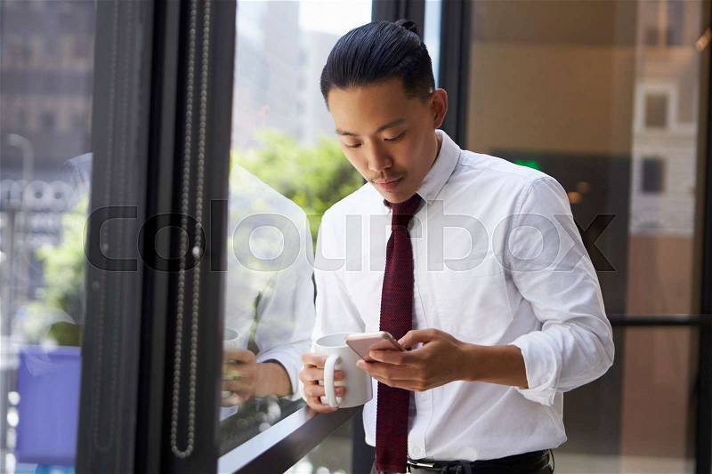 Asian businessman using phone in modern office, close up, stock photo