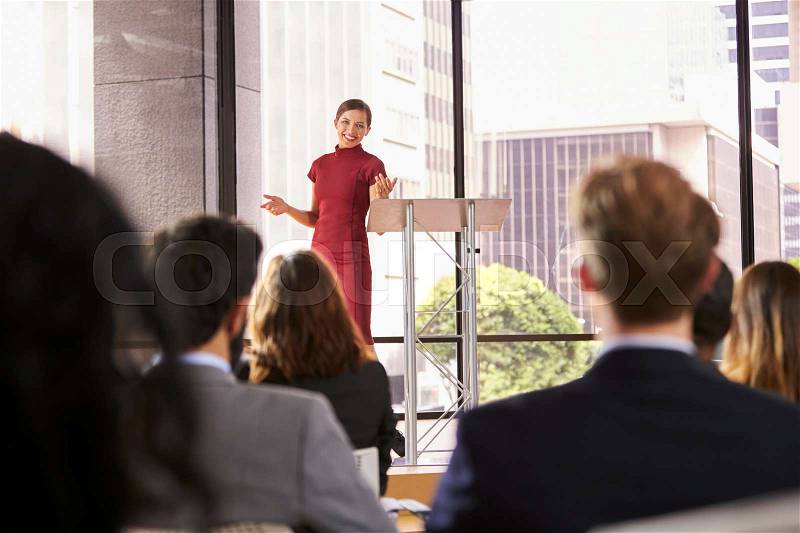 Young woman presenting business seminar gestures to audience, stock photo