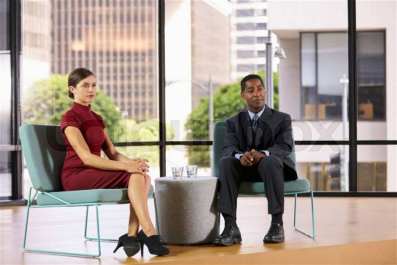 Smartly dressed man and woman on set for a TV interview, stock photo