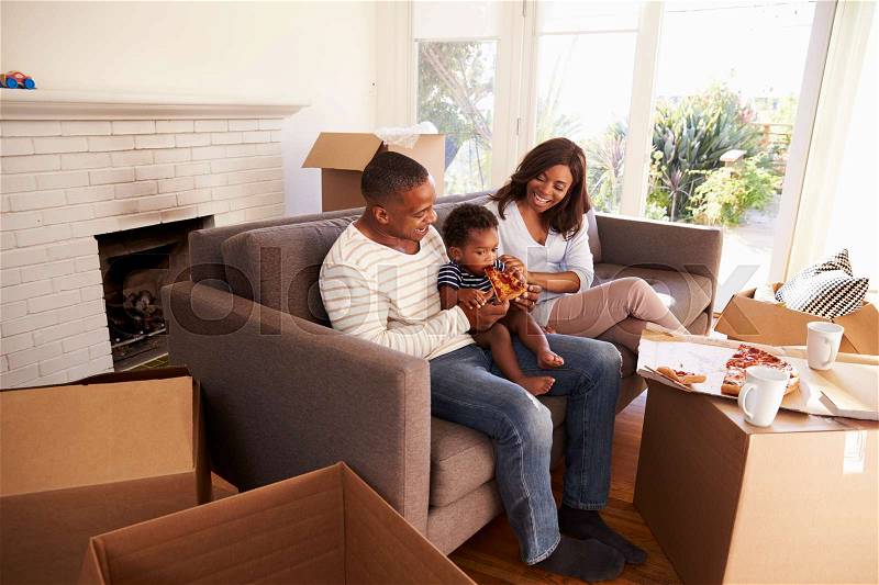 Family Take A Break On Sofa With Pizza On Moving Day, stock photo