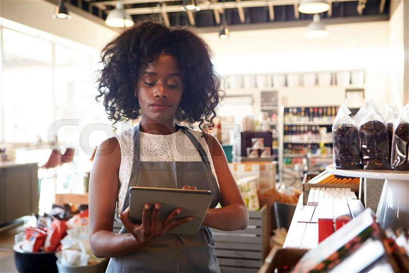 Employee In Delicatessen Checking Stock With Digital Tablet, stock photo