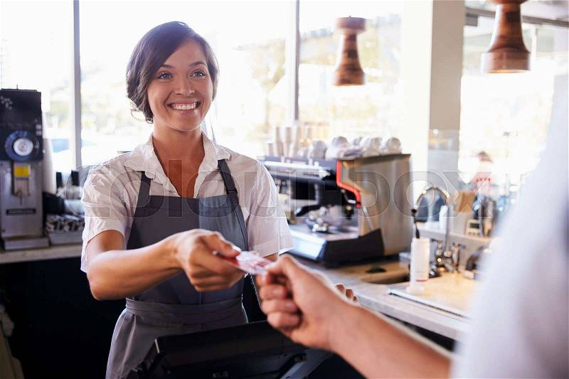 Cashier Accepts Card Payment From Customer In Delicatessen, stock photo
