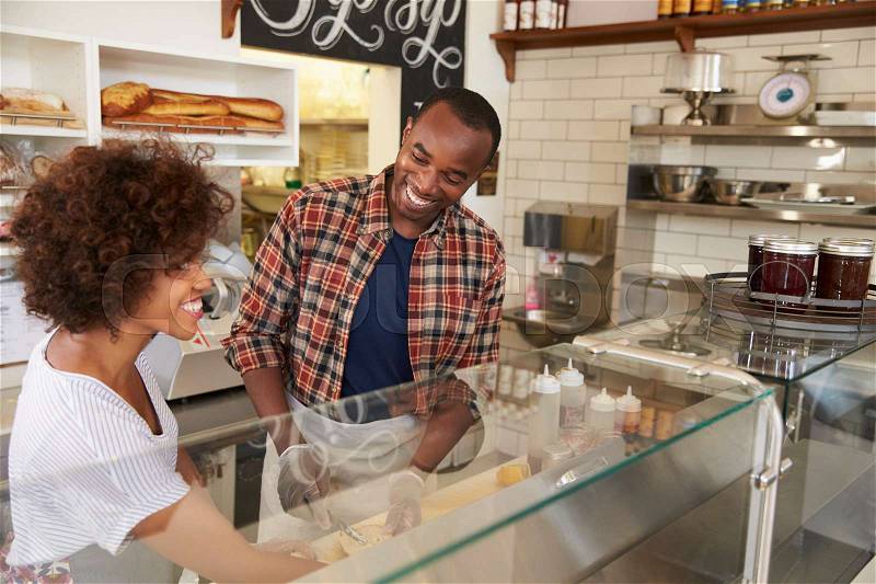 Black couple working behind the counter at a sandwich bar, stock photo