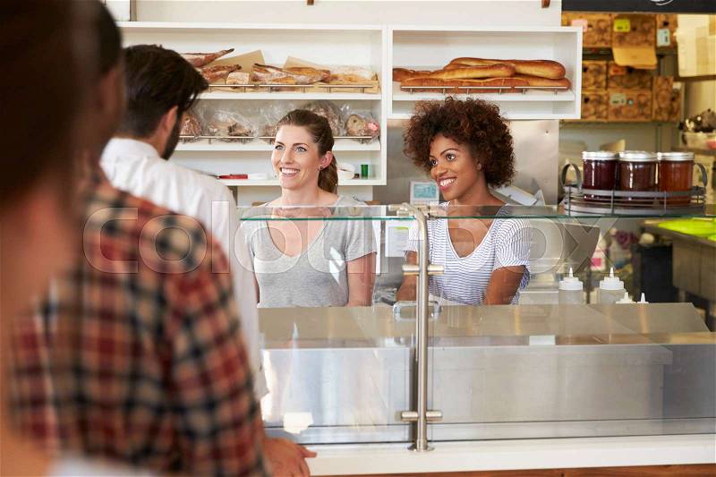 A queue of customers served by two women at a sandwich bar, stock photo