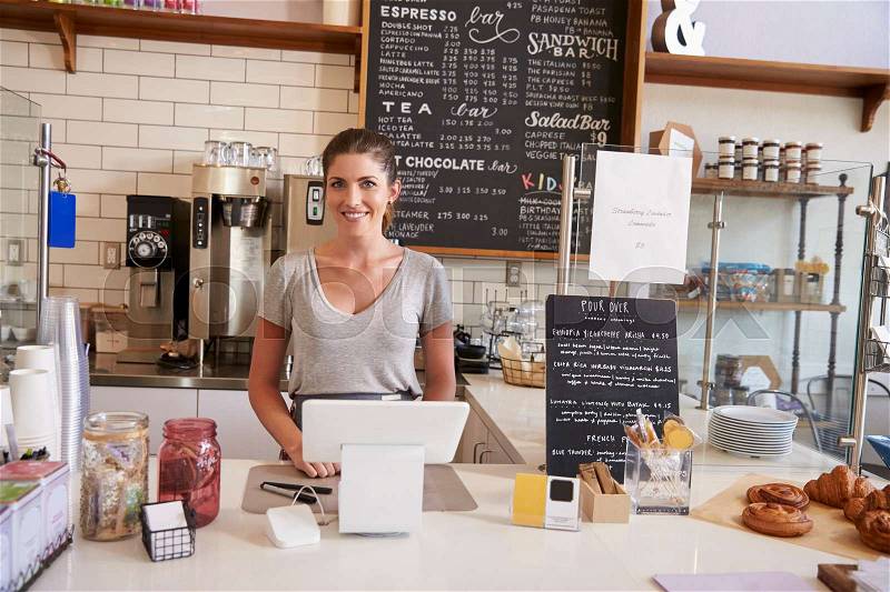 Woman waiting behind the counter at a coffee shop, close up, stock photo