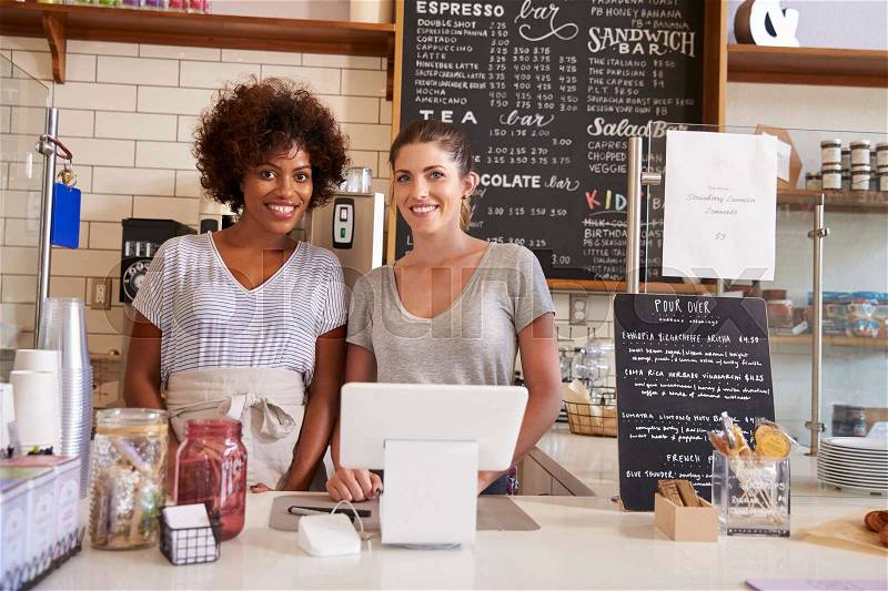 Two women behind the counter at a coffee shop, close up, stock photo