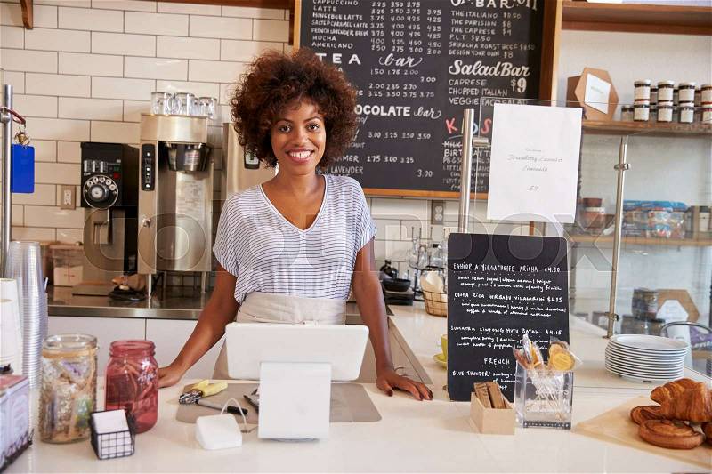 Smiling waitress behind counter at a coffee shop, close up, stock photo
