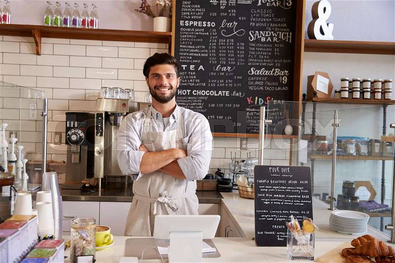 Business owner at the counter of coffee shop, arms crossed, stock photo