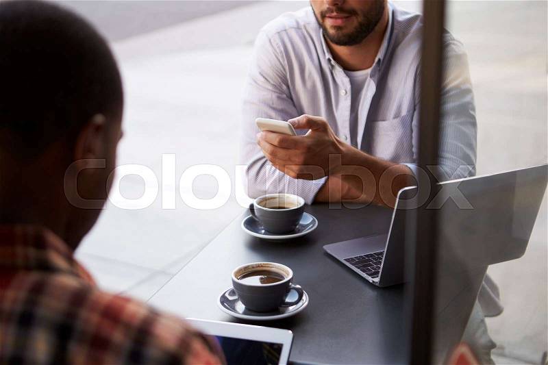 Crop shot of two male friends with coffees outside cafe, stock photo