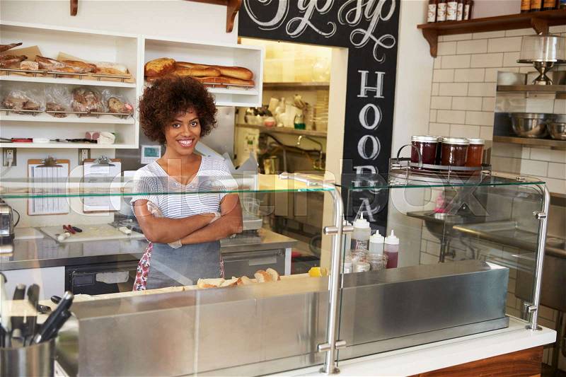 Female business owner behind the counter at a sandwich bar, stock photo