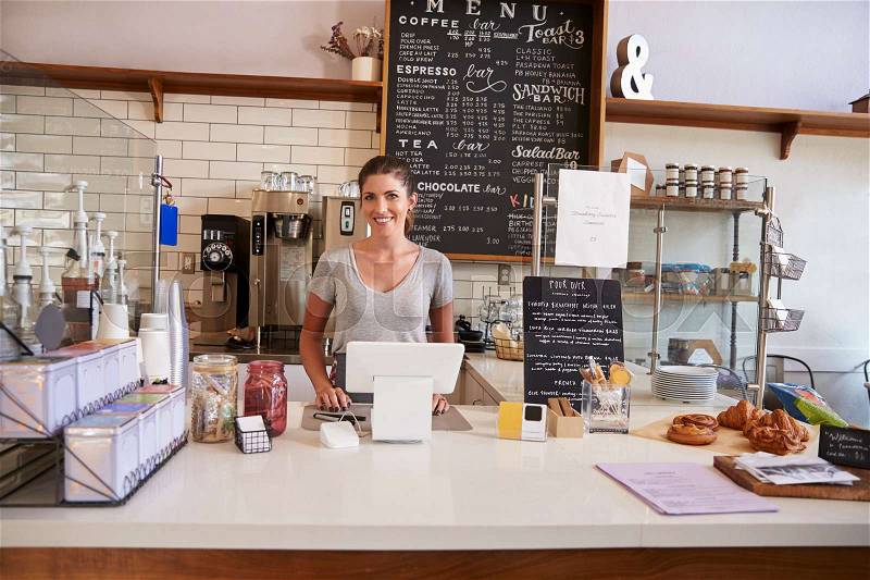 Woman ready to serve behind the counter at a coffee shop, stock photo