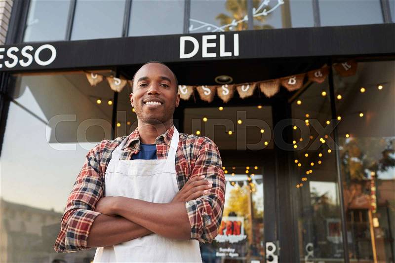 Black male business owner standing outside coffee shop, stock photo