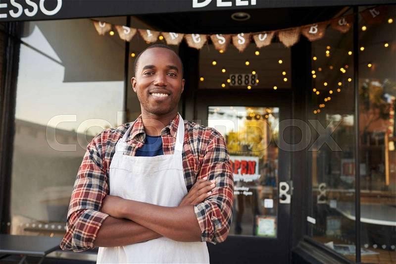 Black male business owner standing outside coffee shop, stock photo