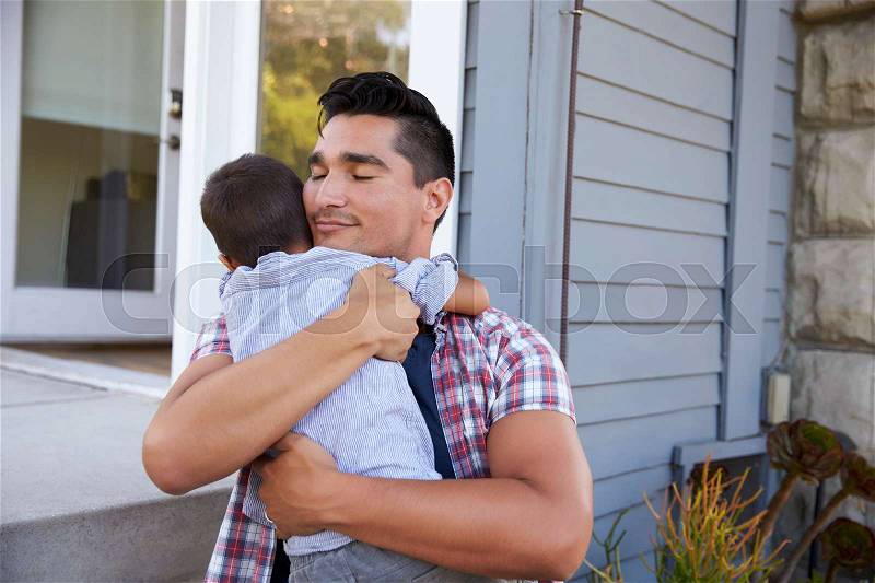 Father Hugging Son Sitting On Steps Outside Home, stock photo