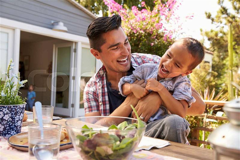 Father And Son Eating Outdoor Meal In Garden Together, stock photo