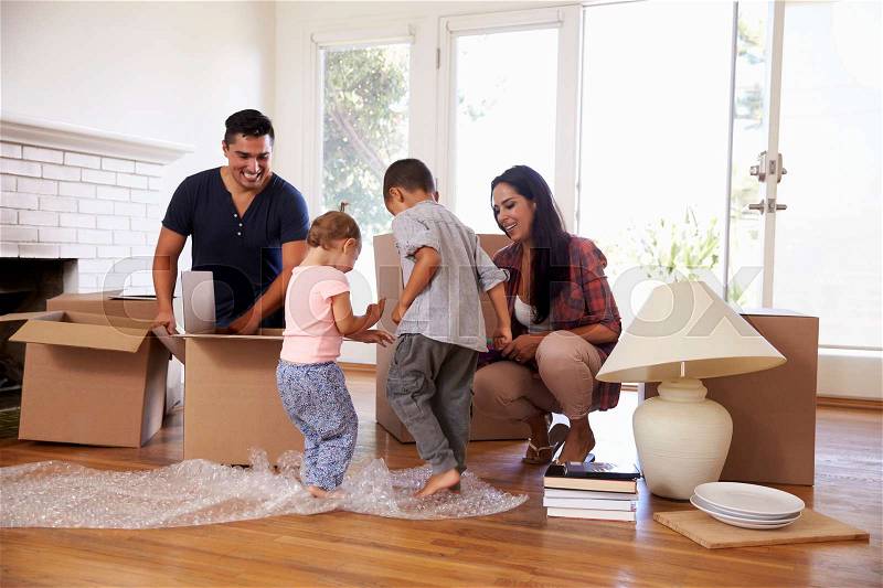 Family Unpacking Boxes In New Home On Moving Day, stock photo