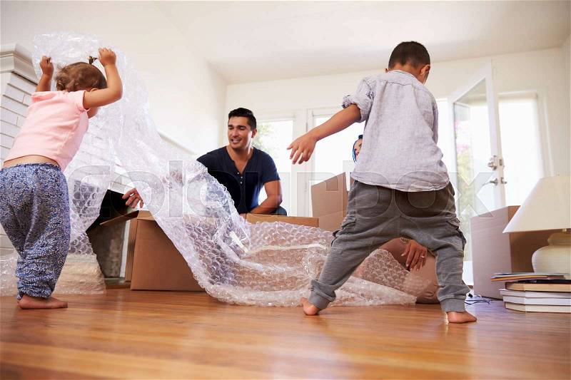 Family Unpacking Boxes In New Home On Moving Day, stock photo