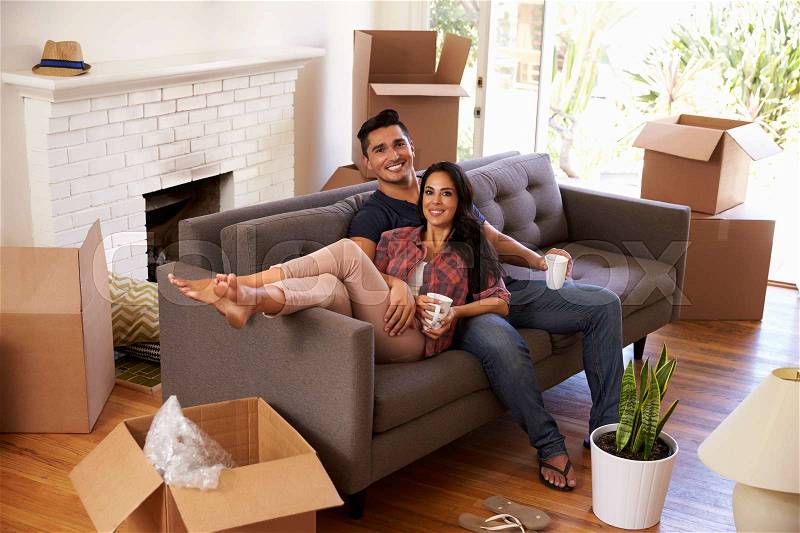 Couple On Sofa Taking A Break From Unpacking On Moving Day, stock photo