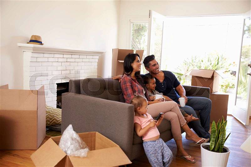 Family On Sofa Taking A Break From Unpacking Watching TV, stock photo