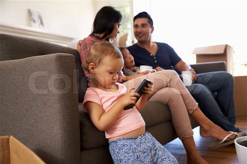 Family On Sofa Taking A Break From Unpacking Watching TV, stock photo