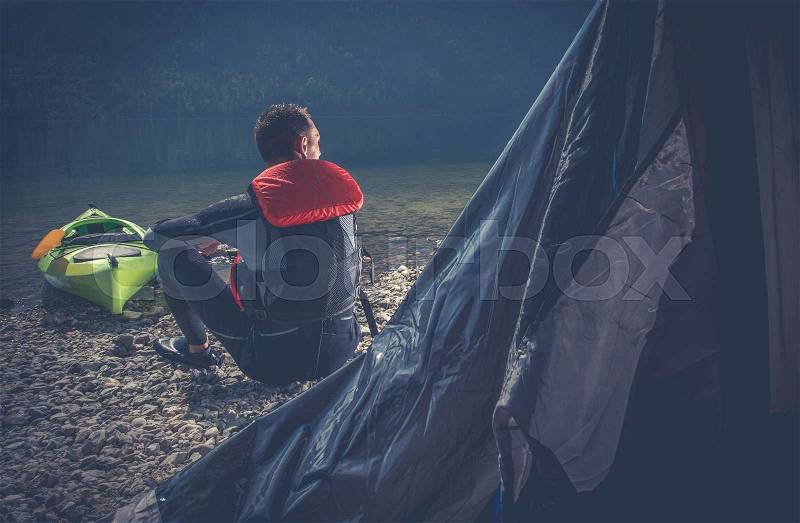 Outdoor Sportsman Camping. Caucasian Men in Wetsuit on the Camping on the Edge of Scenic Lake, stock photo