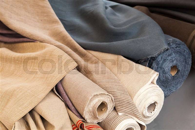 Rolls of natural linen cloth lie on the market counter, stock photo