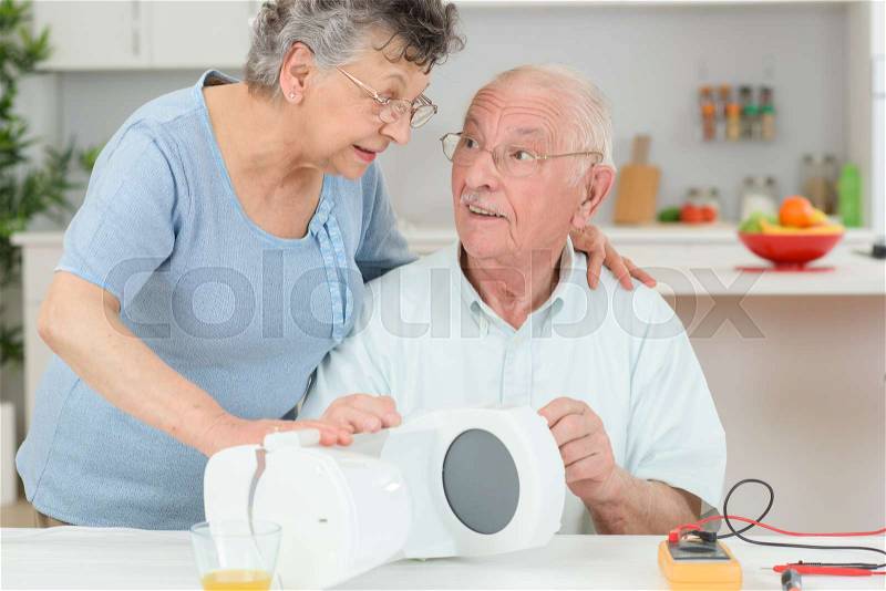 Senior citizen testing electrical appliance, stock photo