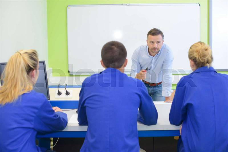 Teacher leaning forward to talk to students, stock photo