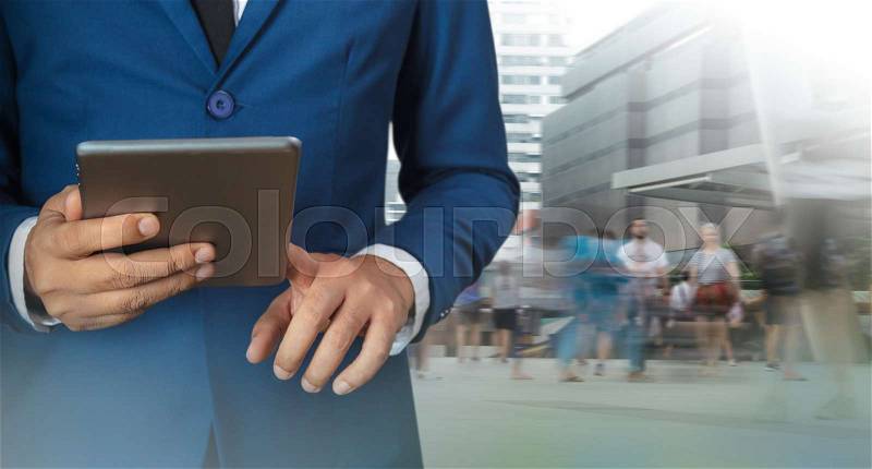 Businessman using digital tablet with modern building and social media, stock photo