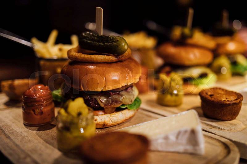 Close up shot of a restaurant burger meal with onion rings, bacon, pickle, chips and garnishes. , stock photo