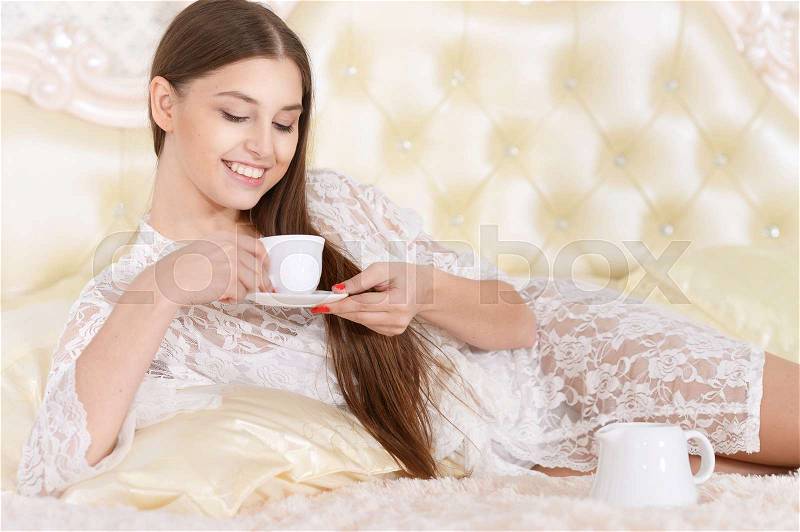Beautiful young woman drinking tea in bed, stock photo