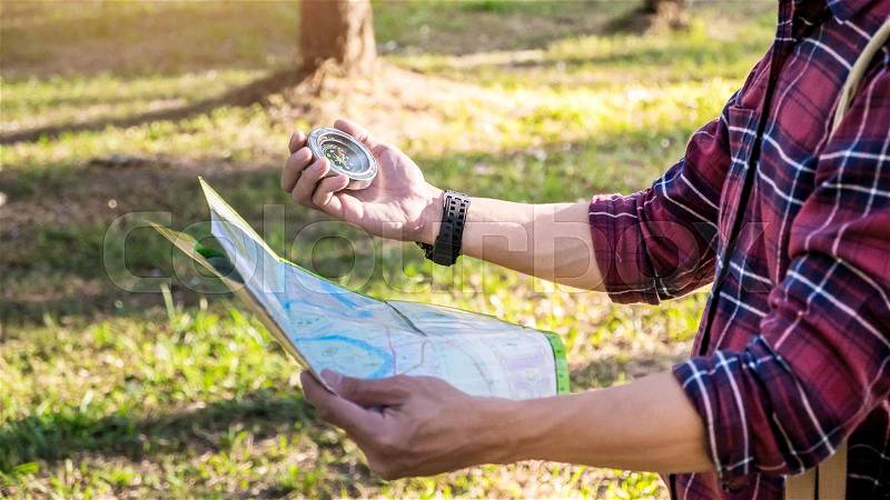 A lost tourist in a hike with compass aiming the direction in the forest, stock photo